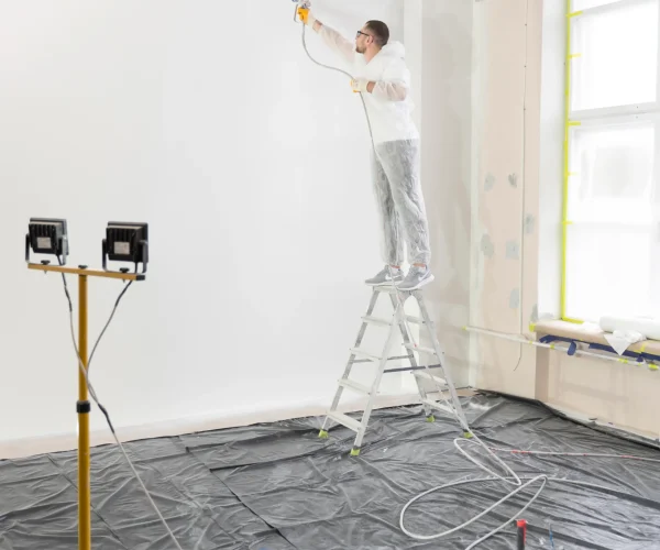 Pintor profesional utilizando una pistola airless para un acabado rápido y uniforme en un piso.